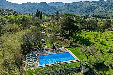 An aerial view of a swimming pool surrounded by trees and mountains