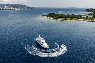 A large white boat is floating in the ocean near a small island