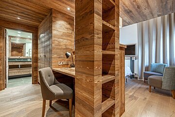 A wooden room with a desk and chair in it