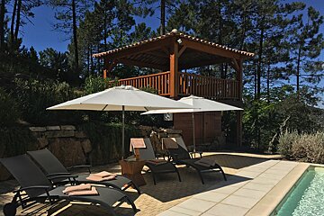 A gazebo with chairs and umbrellas next to a swimming pool