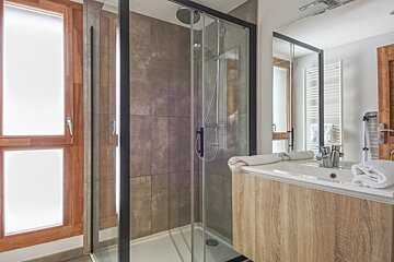 A bathroom with a walk in shower and a sink