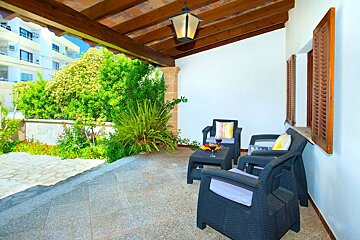 A patio with chairs and a table with a glass of wine on it