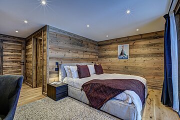 A bedroom with a bed and a painting of a mountain on the wall