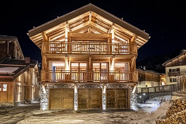 A large wooden house is lit up at night