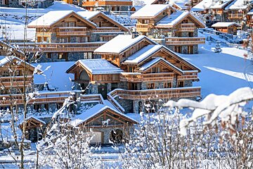 A snowy landscape with a few houses covered in snow