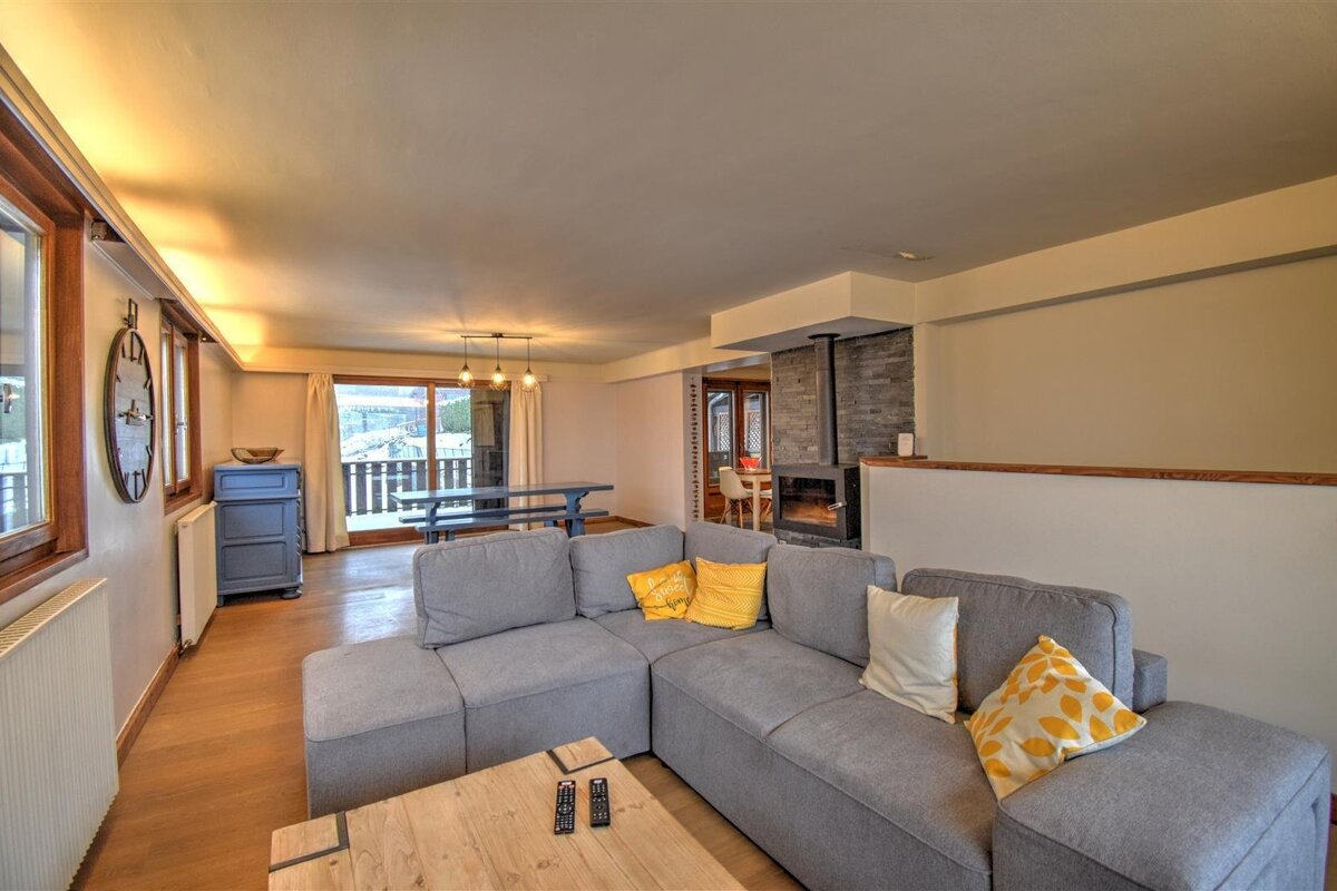 A living room with a sectional couch and a wooden table