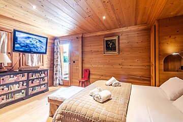 A bedroom with a large flat screen tv above the bed