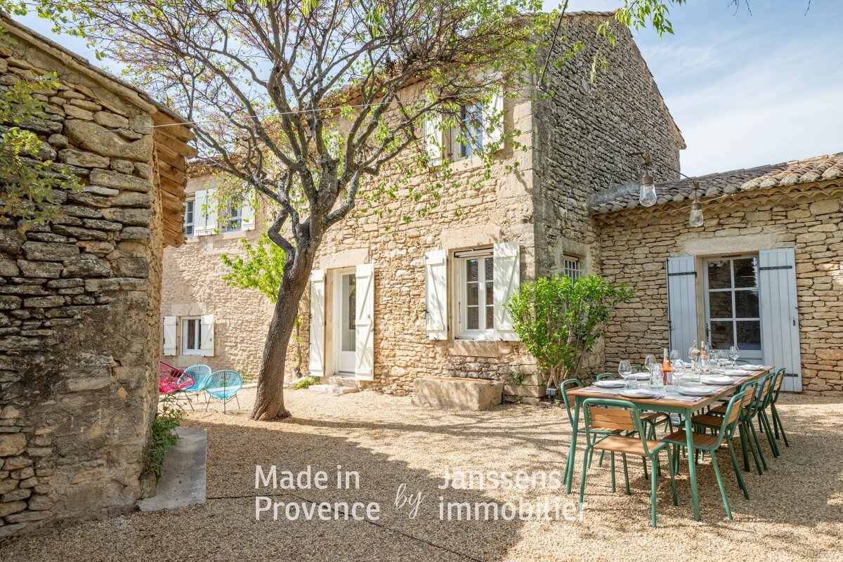 A stone building with a table and chairs in front of it that says made in provence by immobilier