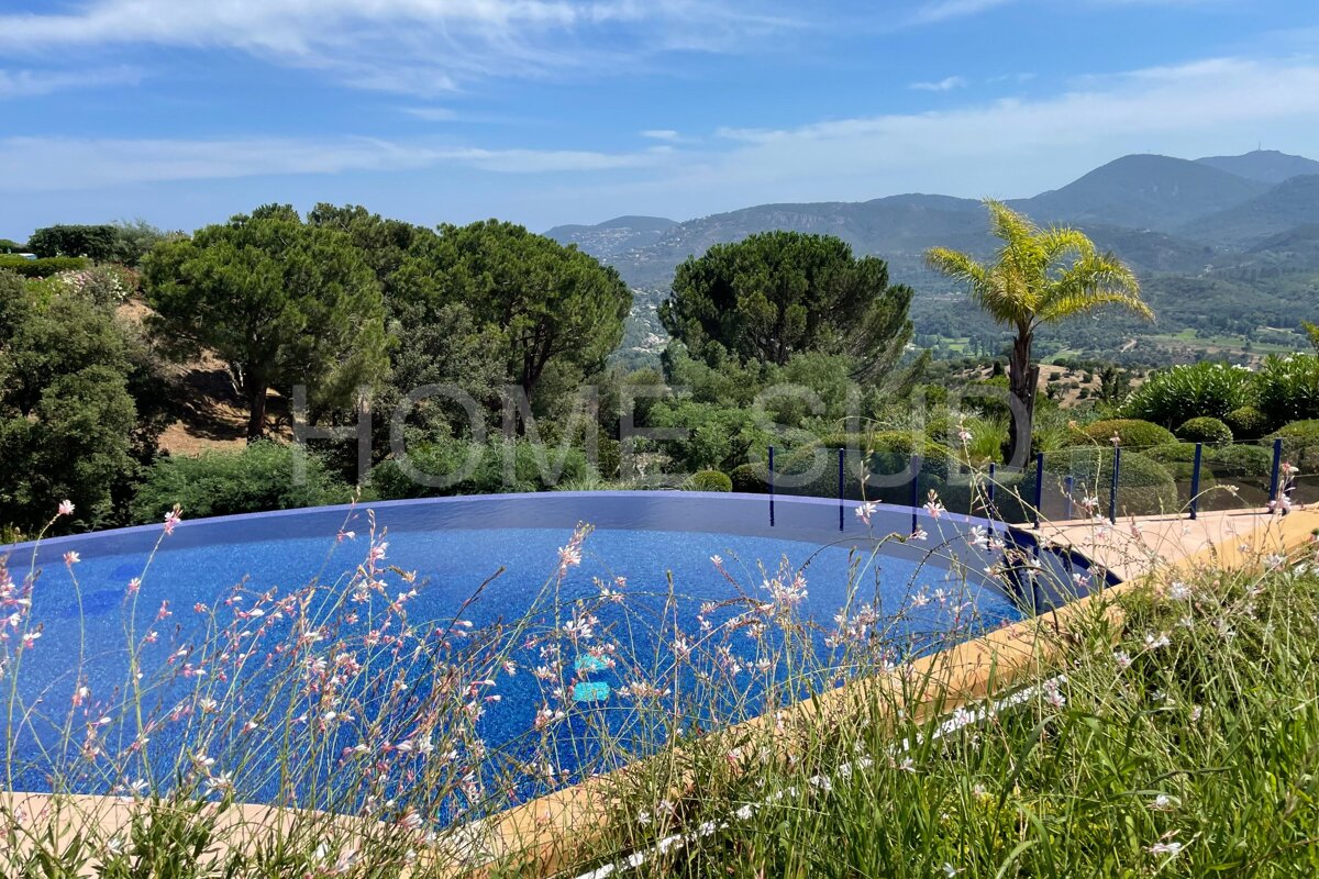 A swimming pool surrounded by tall grass with the word home on the bottom