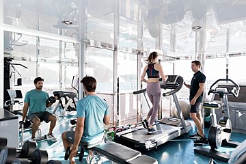 A woman is running on a treadmill in a gym