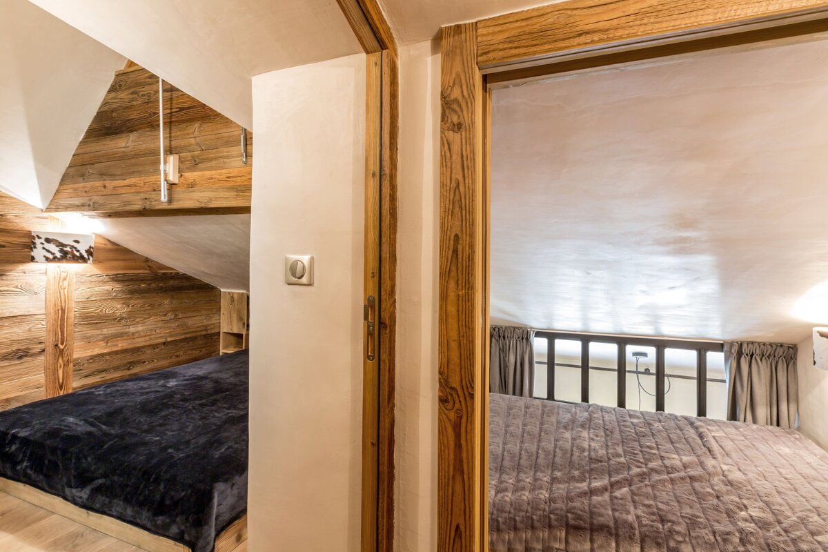 Two cozy loft bedrooms in a rustic wooden cabin, featuring sloped ceilings and comfortable beds.