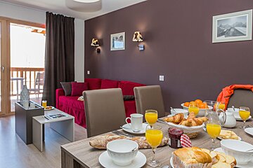 A living room with a red couch and a table set for breakfast