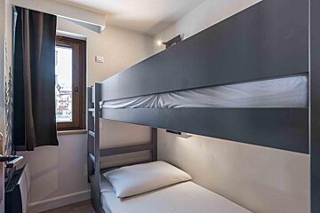 A bunk bed in a small room with a window