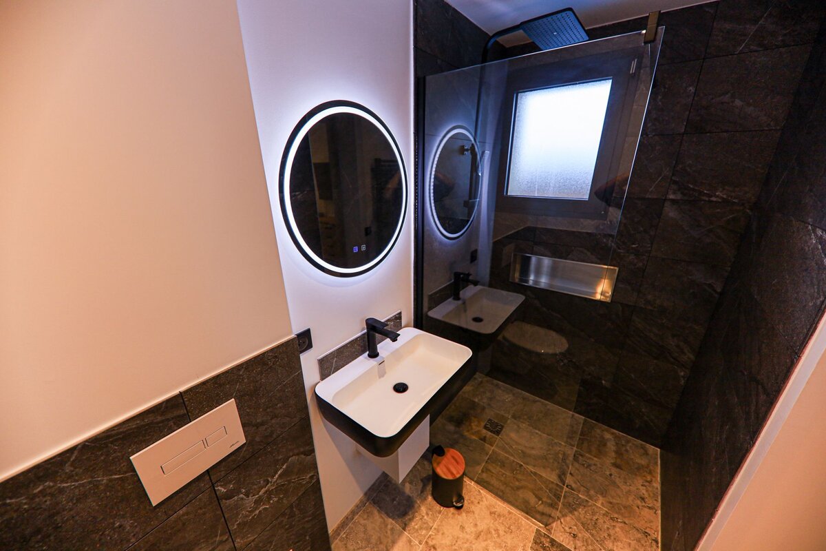 A bathroom with two sinks and a round mirror