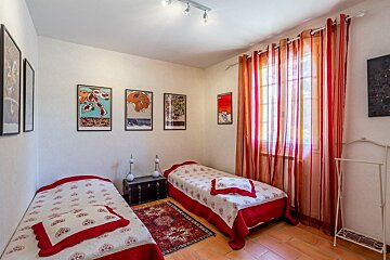 A bedroom with two twin beds and red curtains