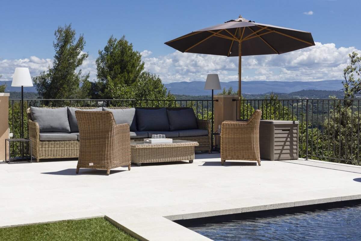 A patio with a couch and chairs under an umbrella