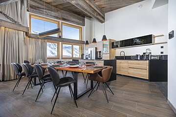 A dining room with a table and chairs and a kitchen