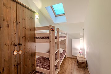 A bunk bed in a room with a skylight above it