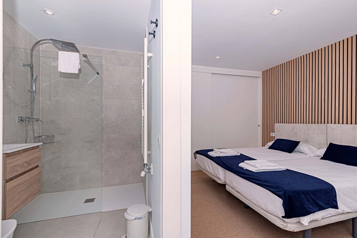 A bedroom with two beds and a walk in shower