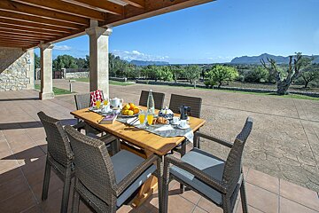 A table and chairs on a patio with mountains in the background