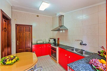 A kitchen with red cabinets and a bowl of fruit on the counter