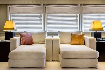 A living room with two white chairs and two lamps
