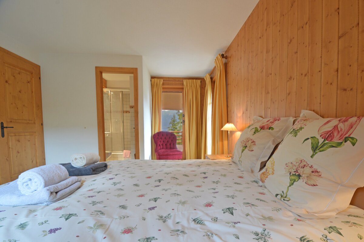 A bedroom with a floral comforter and pillows