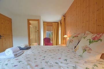 A bedroom with a floral comforter and pillows