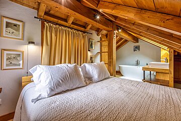 A bedroom with a large bed and a bathtub