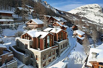 A row of snow covered buildings with mountains in the background