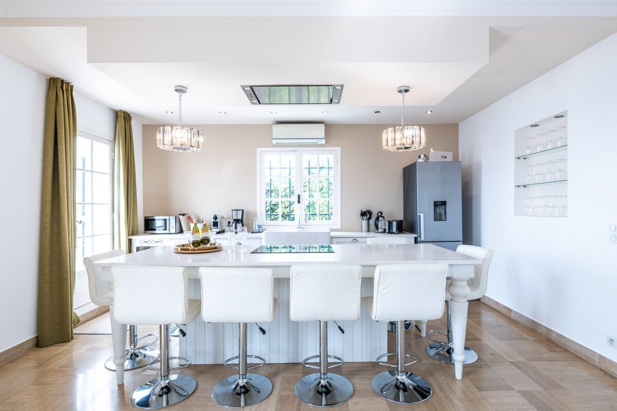 A kitchen with a large island and white chairs