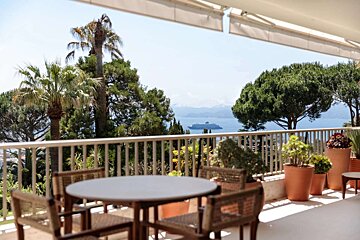 A table and chairs on a balcony overlooking the ocean