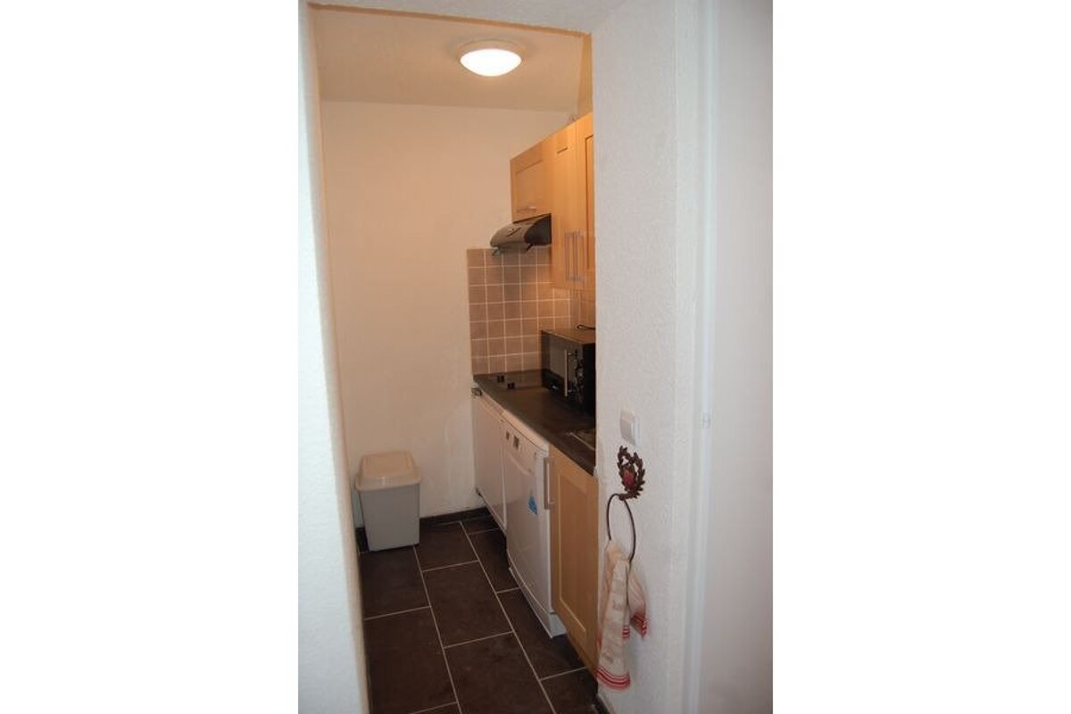 A kitchen with a microwave and a trash can