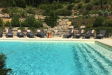 A row of lounge chairs sit near a swimming pool