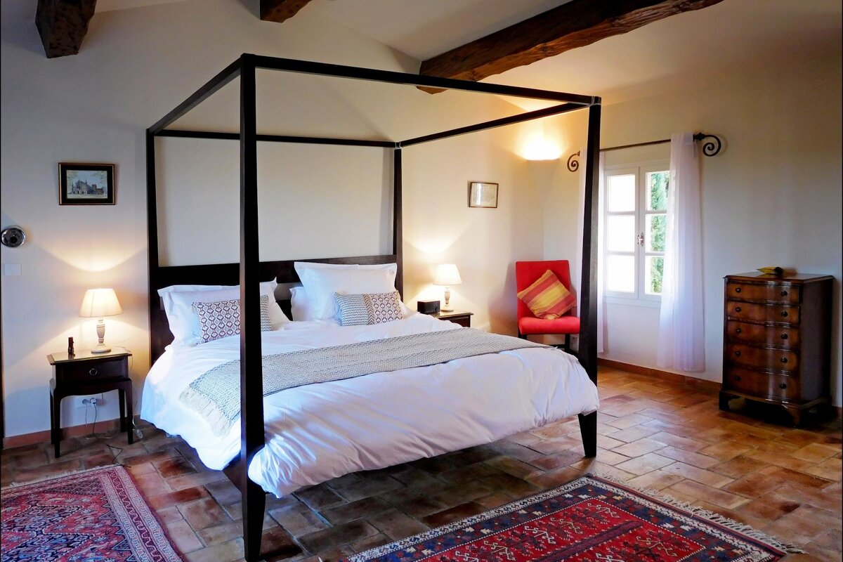 A bedroom with a four poster bed and a rug