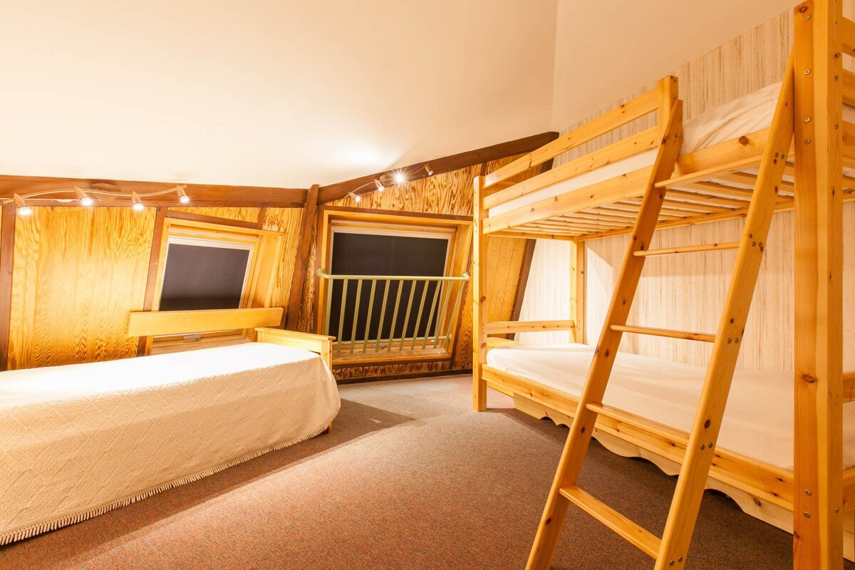 A bunk bed with a ladder is next to a single bed