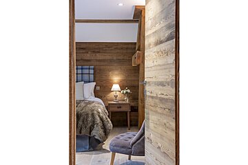 A bedroom with a wooden wall and a bed