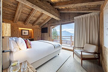 A bedroom with a large bed and a chair