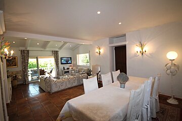 A living room with a table and chairs and a flat screen tv