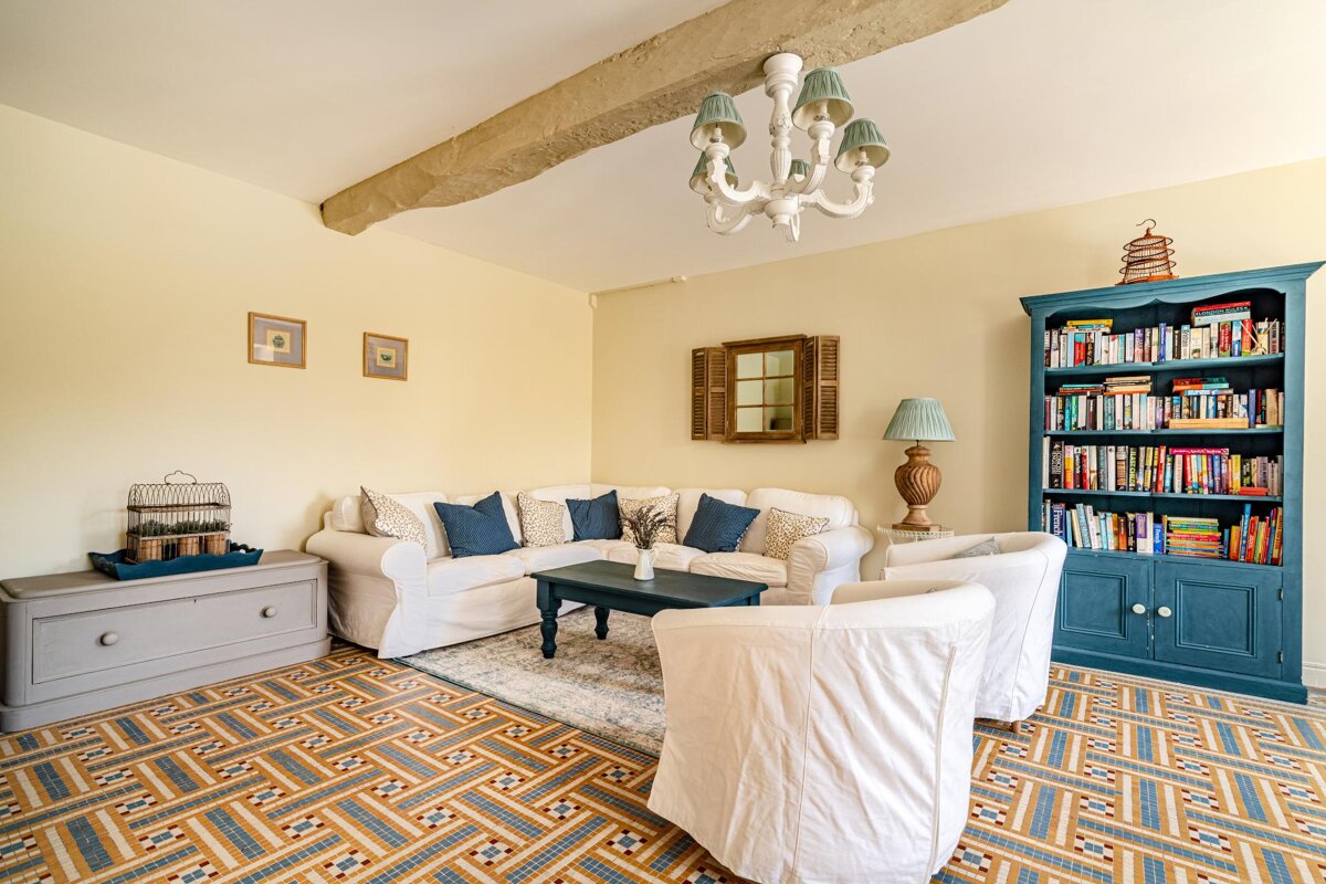 A living room with a couch and chairs and a bookshelf filled with books