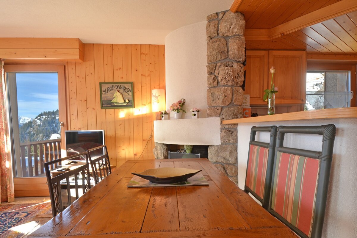 A wooden dining room table with a sign on the wall that says 