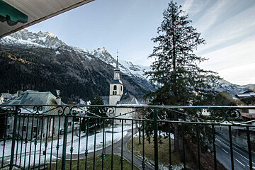A balcony with a view of a church in the mountains