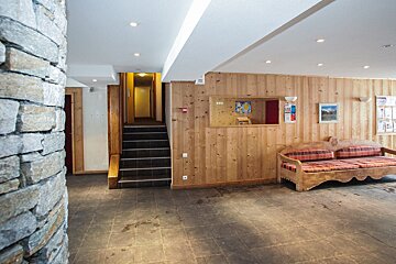A room with wood paneling and a couch and stairs