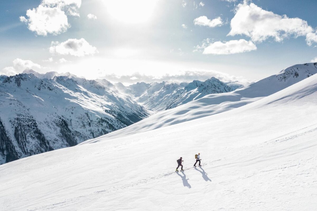 Two people skiing down a snow covered mountain