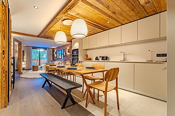 A kitchen with a table and chairs and a wooden ceiling