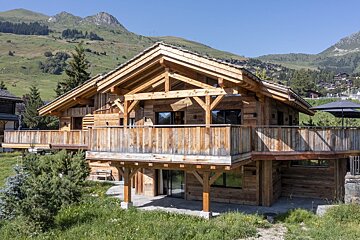 A large wooden house with a mountain in the background