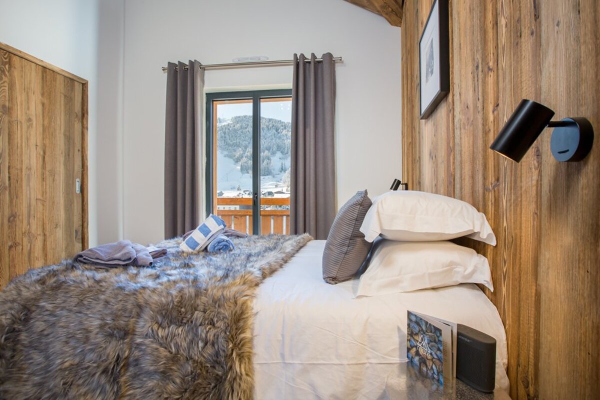 A bedroom with a bed and a window with mountains in the background