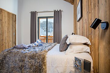 A bedroom with a bed and a window with mountains in the background