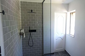A bathroom with grey tiles and a black shower head