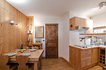 A kitchen with a table and chairs and a bottle of wine